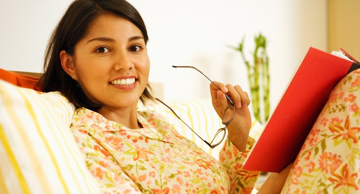 woman sitting on couch reading a book